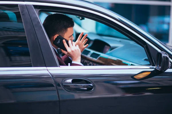 Un hombre de negocios serio está teniendo una conversación en su teléfono mientras — Foto de Stock