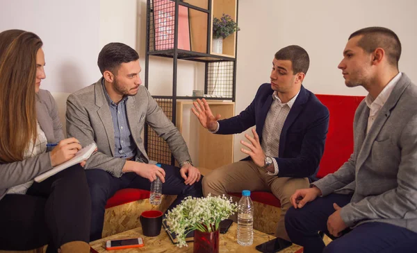 Cuatro jóvenes empresarios hablando en un lugar de oficina pelsant mientras —  Fotos de Stock