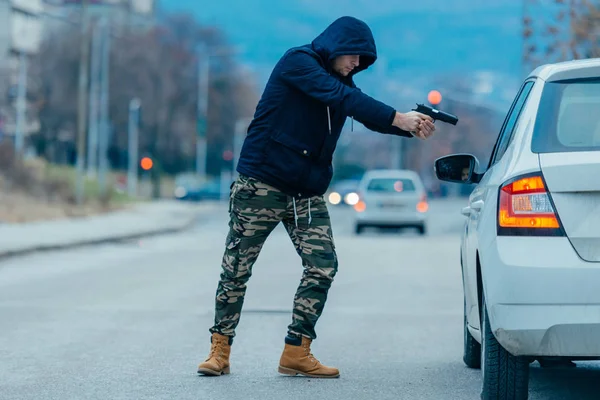 Gángster con un arma tratando de robar a un tipo que está sentado en su — Foto de Stock