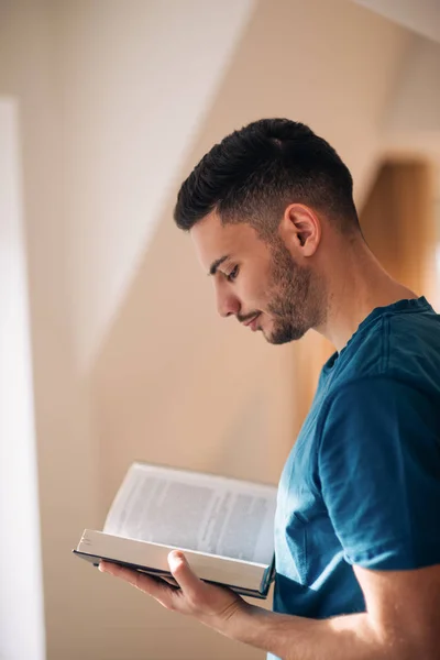 Student czytając książkę stojąc i spacerując w pokoju ne — Zdjęcie stockowe