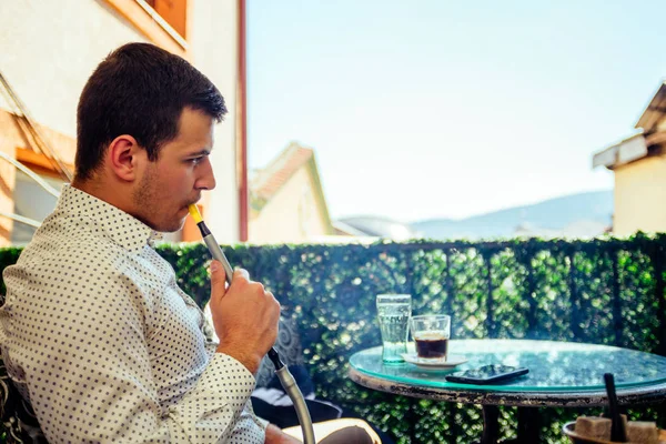 Hombre de negocios urbano relajándose en el balcón mientras fuma shisha —  Fotos de Stock
