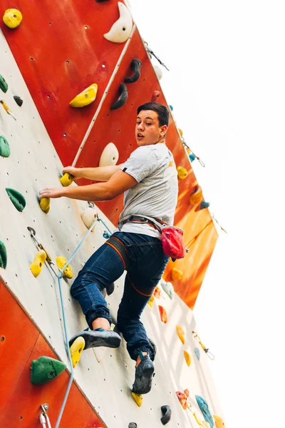 Sportovní muž vyleze na umělou skalní stěnu — Stock fotografie