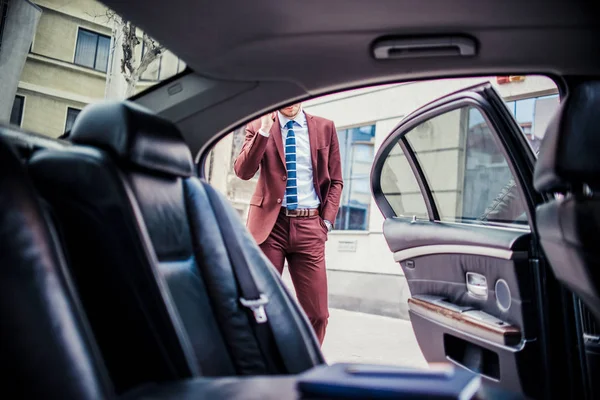 Elegante empresário falando no celular perto da limusina — Fotografia de Stock