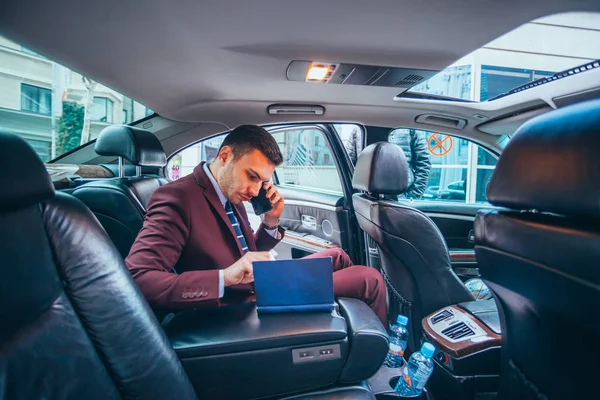 Biznesmen, siedząc w limuzynie podczas rozmowy na jego czytanie telefon — Zdjęcie stockowe