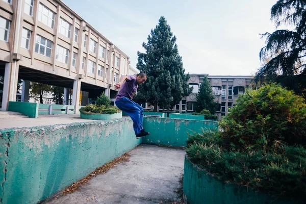 コンクリートの壁を飛び越えるパルクールを訓練しながらストロングマン — ストック写真