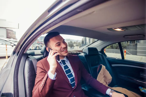 Un hombre de negocios sonriente conduciendo en una limusina — Foto de Stock