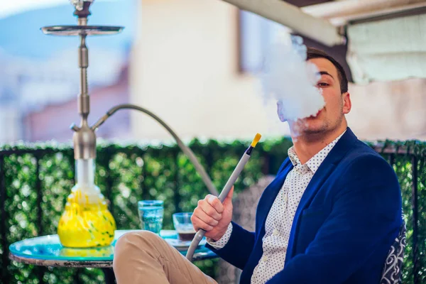 Un empresario guapo con pelo facial fumando shisha (nargile ) —  Fotos de Stock
