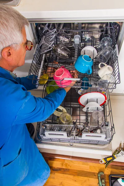 Εργάτης γήρατος που φτιάχνει τη μηχανή του πλυντηρίου πιάτων — Φωτογραφία Αρχείου