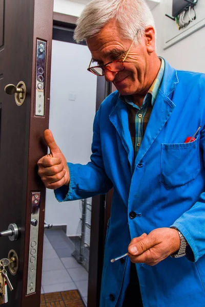 Trabajador repara la cerradura de la puerta en el pasillo —  Fotos de Stock