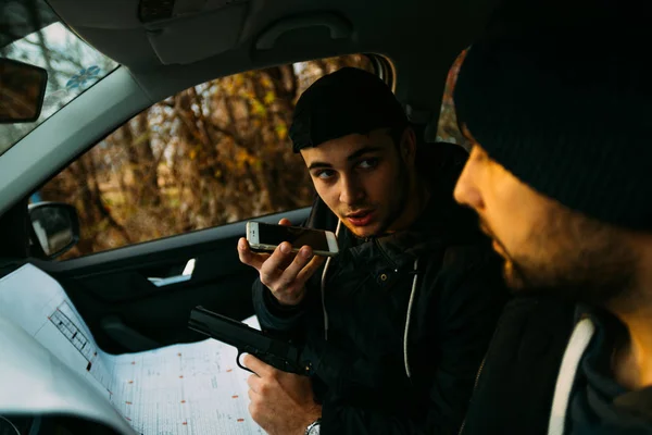 Zwei bewaffnete Banditen sitzen in einem Auto und planen ihren nächsten Raubüberfall, — Stockfoto