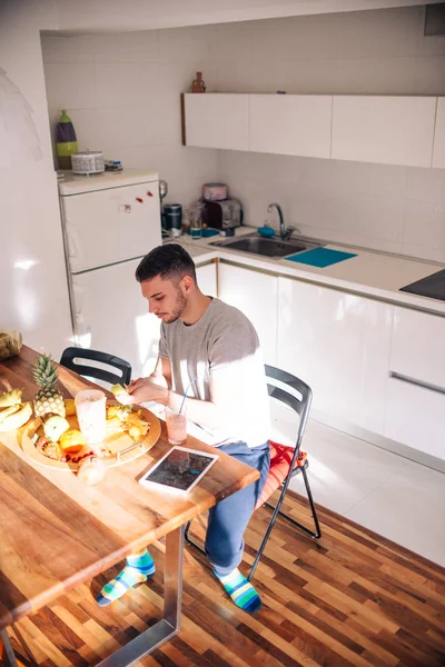 Gesunder Mann wählt die Früchte sorgfältig aus und schneidet sie für sich — Stockfoto