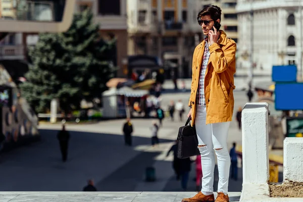 Empresário urbano de casaco amarelo falando no celular — Fotografia de Stock