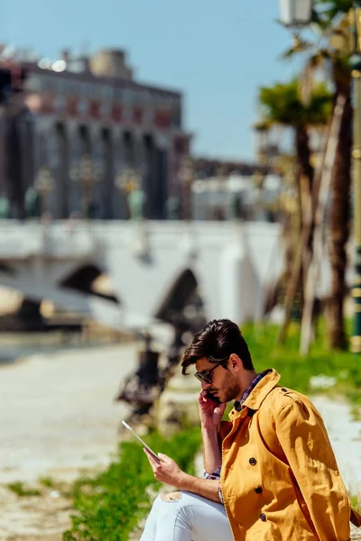 Uomo elegante in cappotto giallo in luogo urbano parlando sul cellulare — Foto Stock