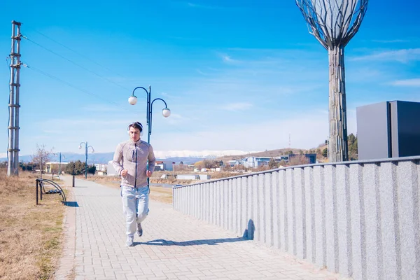 Een hijgend atleet lopen snel op een track tijdens het dragen van headphon — Stockfoto