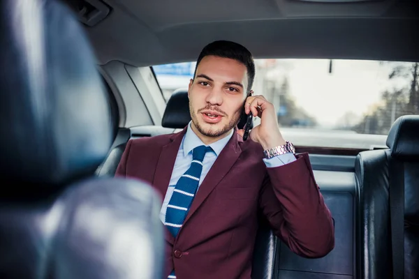 Gazdag üzletember egy limuzinban vezetés és beszélni a telefon — Stock Fotó
