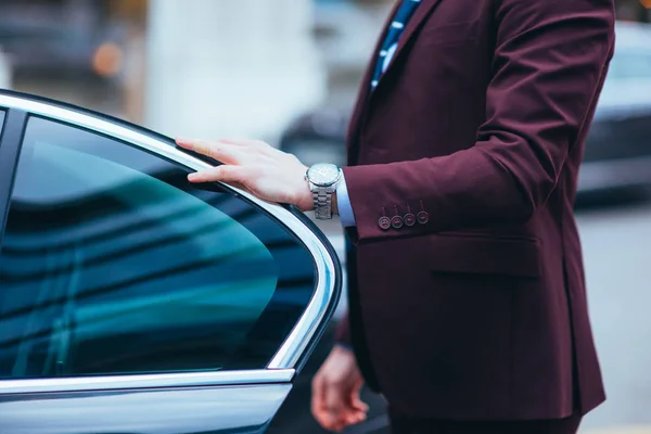 Empresário segurando a porta de sua limusina mostrando seu relógio a — Fotografia de Stock