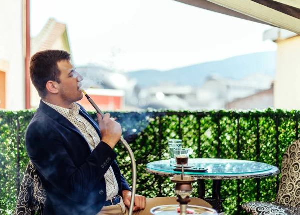 Hombre de negocios urbano relajándose en el balcón mientras fuma shisha —  Fotos de Stock