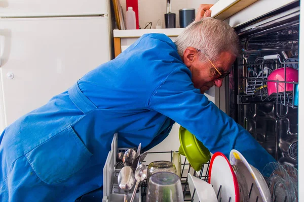 Handyman abriendo los lavavajillas en la cocina blanca — Foto de Stock