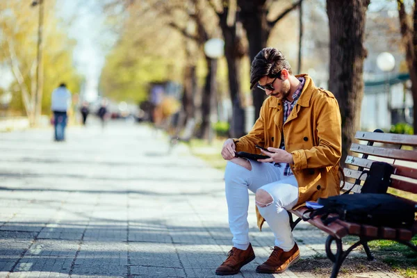 Geschäftsmann im gelben Mantel arbeitet im Park an Tablet — Stockfoto