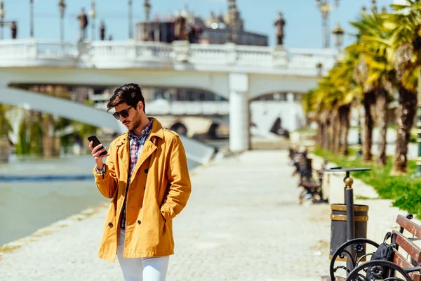 Uomo d'affari urbano in cappotto giallo che parla sul cellulare — Foto Stock