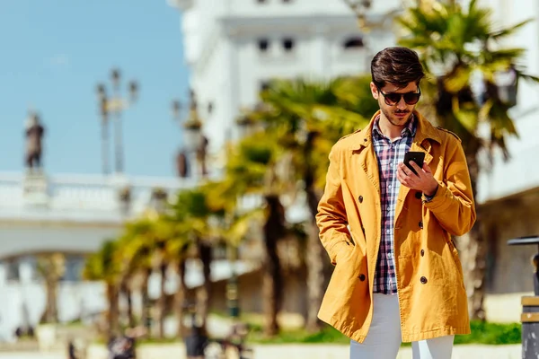 Giovane uomo a piazza della città sms messaggio sul telefono cellulare — Foto Stock
