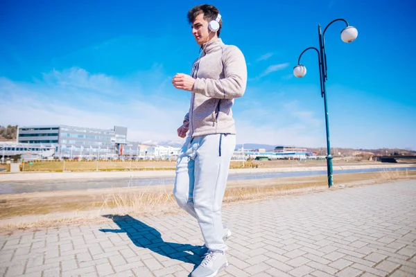 Sportieve jonge man loopt op een spoor naast een rivier terwijl slijtage — Stockfoto