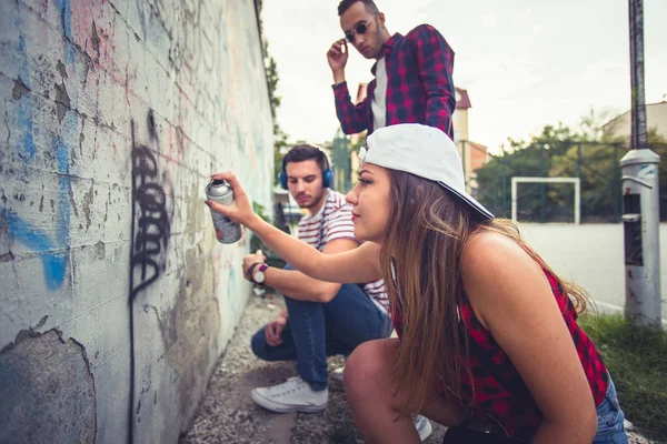 Tres amigos escribiendo graffiti en la pared — Foto de Stock