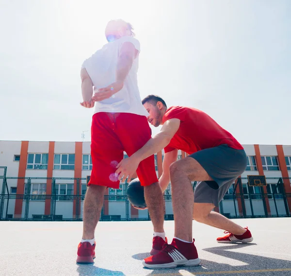 赤いスポーツのエキュアップメントを着た2人の白人の友人がバスケットを演奏 — ストック写真
