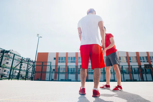 Dos amigos caucásicos con equitación deportiva roja jugando basket — Foto de Stock