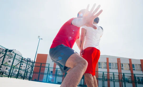 Due amici caucasici che indossano attrezzature sportive rosse che giocano a basket — Foto Stock