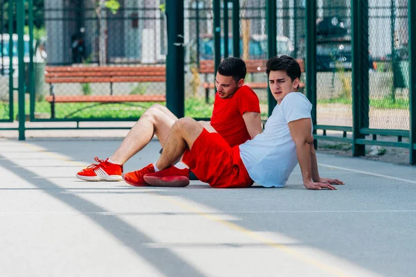 Två vänner efter en lång hård basket match har lite vila på — Stockfoto