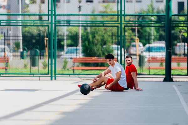 Dva přátelé po dlouhé basketbalové hře mají odpočinek na — Stock fotografie