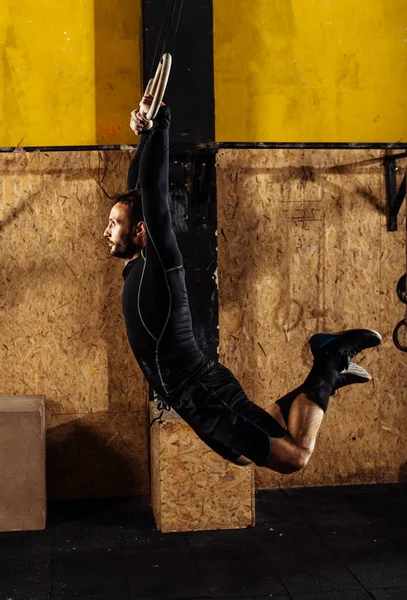 Muscular jovem fazendo pull-ups em anéis — Fotografia de Stock