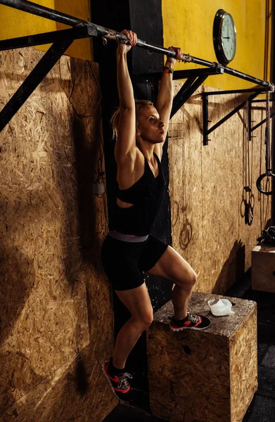 Kobieta wykonuje podciąganie w barze w crossfit siłowni centrum — Zdjęcie stockowe