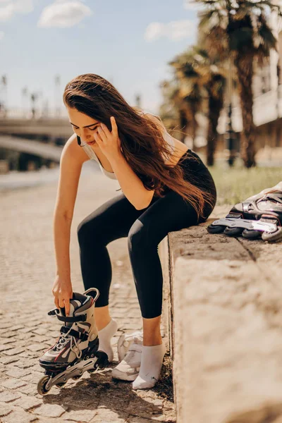 Fröhliche junge Frau auf Rollschuhen sitzt in der Stadt — Stockfoto