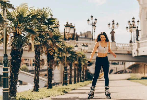 Happy joyful young woman wearing roller skates in town — Stock Photo, Image