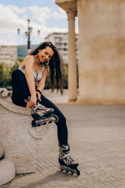 Ευτυχισμένη χαρούμενη νεαρή γυναίκα φορώντας πατίνια στην πόλη — Φωτογραφία Αρχείου