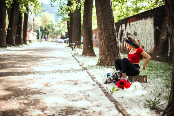 女の子が座って、屋外でスケートを置く — ストック写真