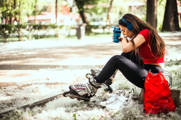 Femeia ia o pauză, bea apă, în timp ce ascultă muzică — Fotografie, imagine de stoc