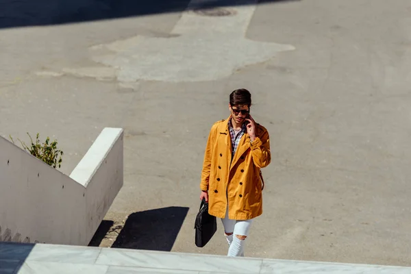 Chico guapo con abrigo amarillo hablando por teléfono — Foto de Stock