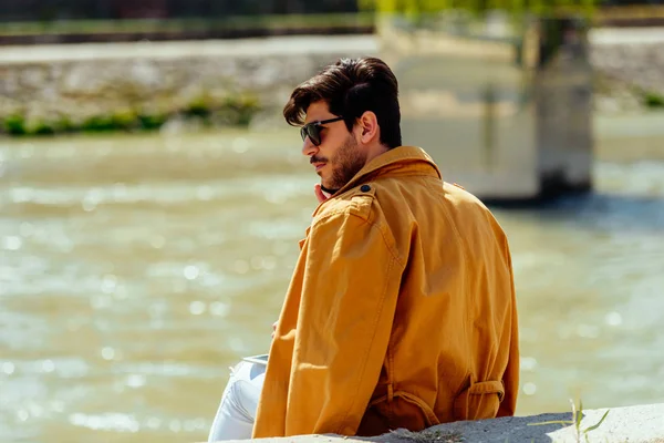 Empresario con abrigo amarillo relajándose cerca del río — Foto de Stock