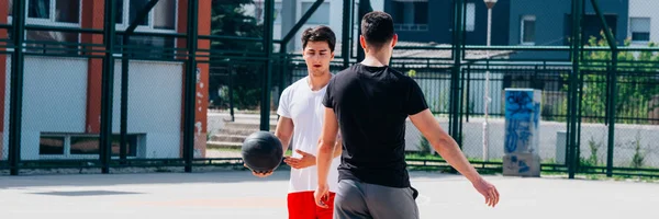 Два сильных баскетболиста играют в мяч на городской бейсбольной площадке — стоковое фото