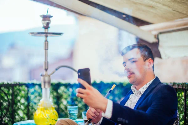 Un hombre de negocios feliz está fumando shisha (hookah) y mirando hola —  Fotos de Stock