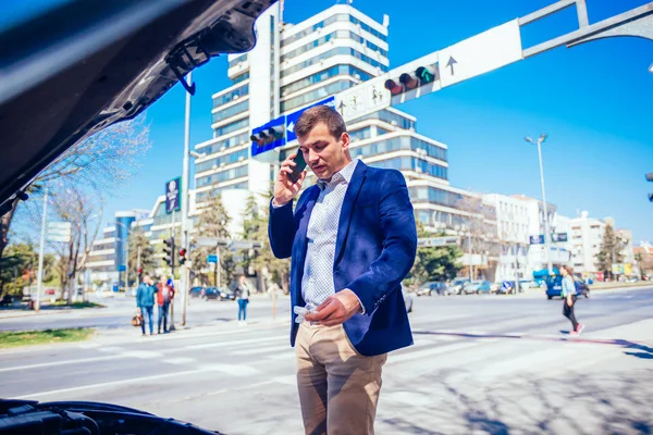 Jovem empresário está falando em seu telefone enquanto olha sob th — Fotografia de Stock