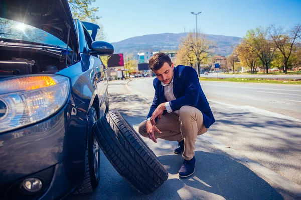 Rozzlobený obchodník se snaží vyměnit si píchlou pneumatiku za zásuvku. — Stock fotografie