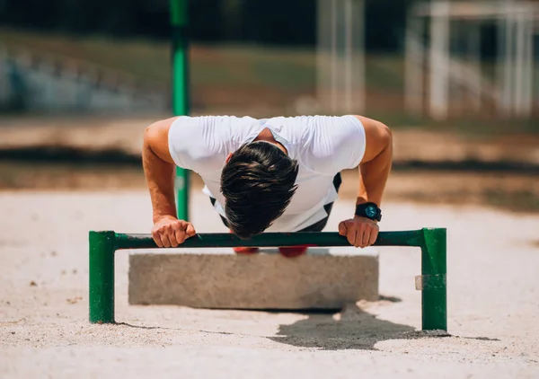 Atleet man in het stadspark maakt een push-up — Stockfoto