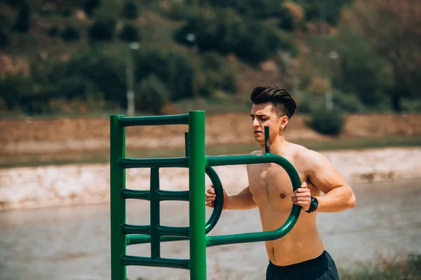 Fitter Mann trainiert am Strand auf Klimmzugstange — Stockfoto