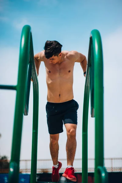 Oefening man workout uit armen op dips horizontale staven — Stockfoto
