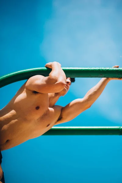 Hombre sin camisa haciendo ejercicio en barra horizontal al aire libre —  Fotos de Stock