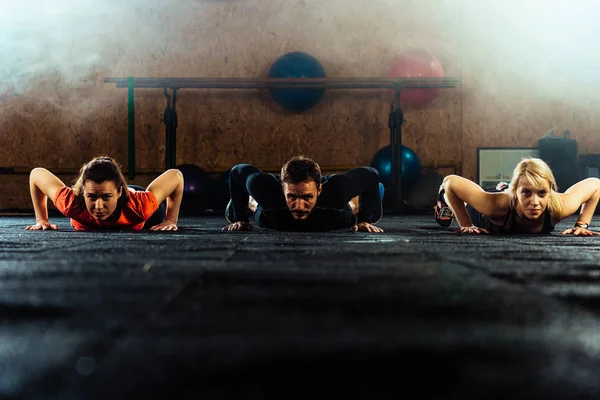Fitt fiatalok fekvőtámaszoznak egy edzőteremben — Stock Fotó